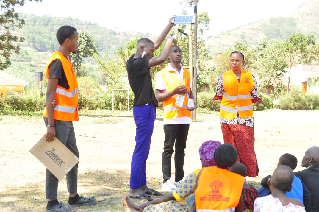 Volunteer holding up a solar lantern to demonstrate it to seated families